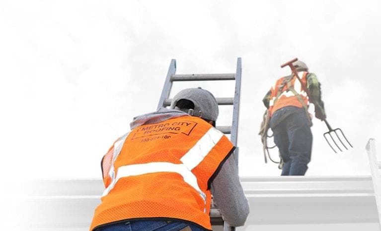 Two Metro City Roofing crew in orange vests climbing a roof to begin a roof replacement in Denver, Colorado